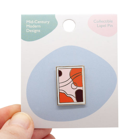 mid-century modern art piece. light pink, orange, plum and white colors in gold enamel. Pin is on backing card, being held by a hand, over white background.