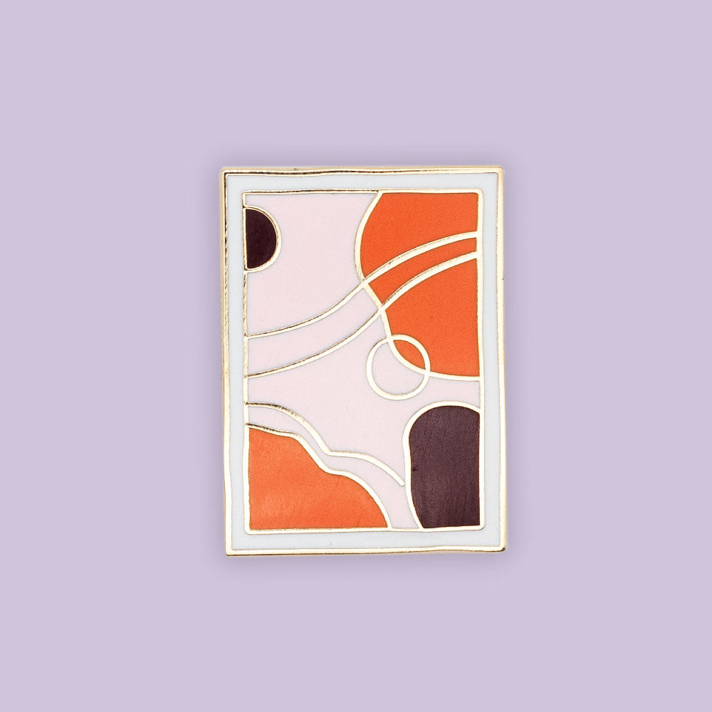 mid-century modern art piece. light pink, orange, plum and white colors in gold enamel. Pin is over purple background 