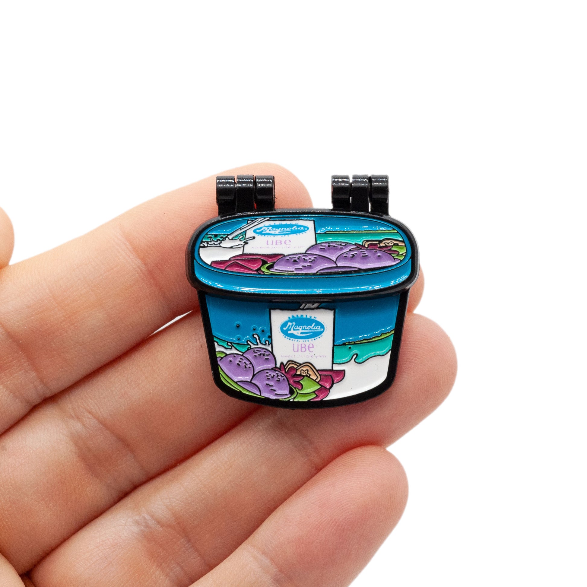 magnolia ice cream tub enamel pin being held by a hand over a white background.