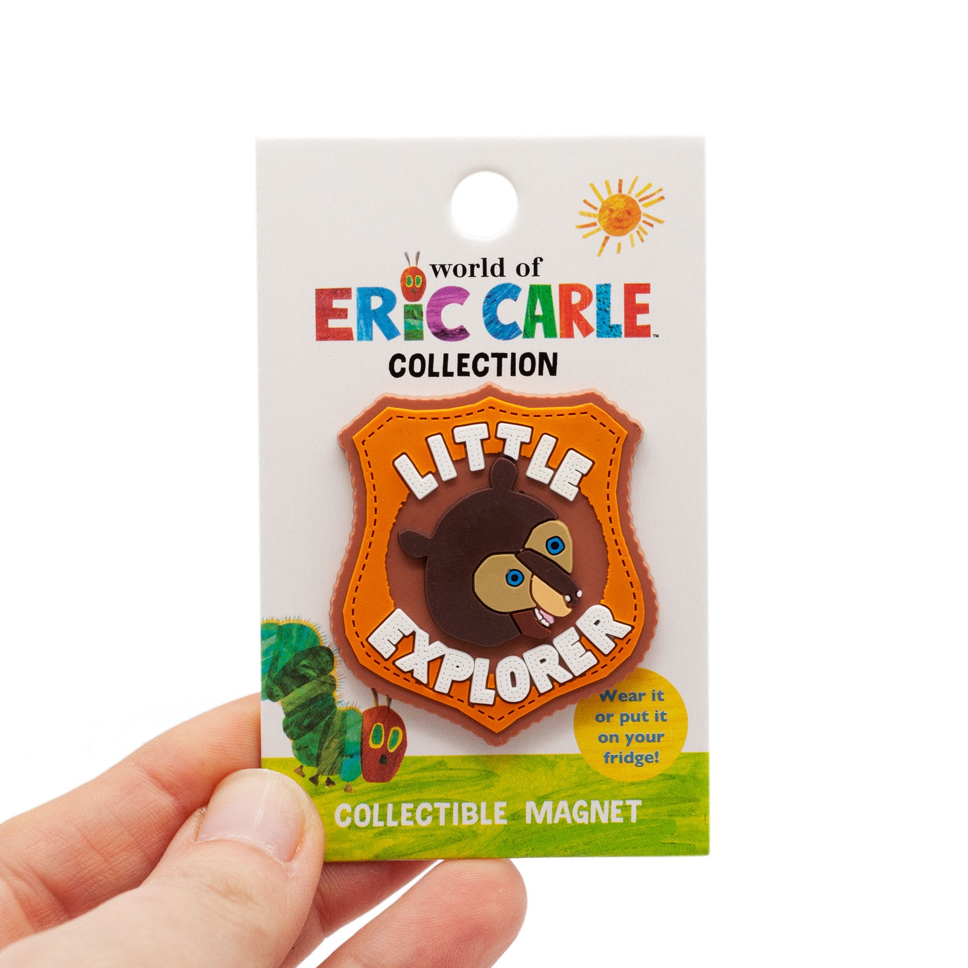 Little Explorer magnet made of soft PVC. Bown bear in the center with letter above and below bear. Colors include light brown, orange , dark brown, blue eyes, and white lettering. Lettering says "little explorer". on backing card.