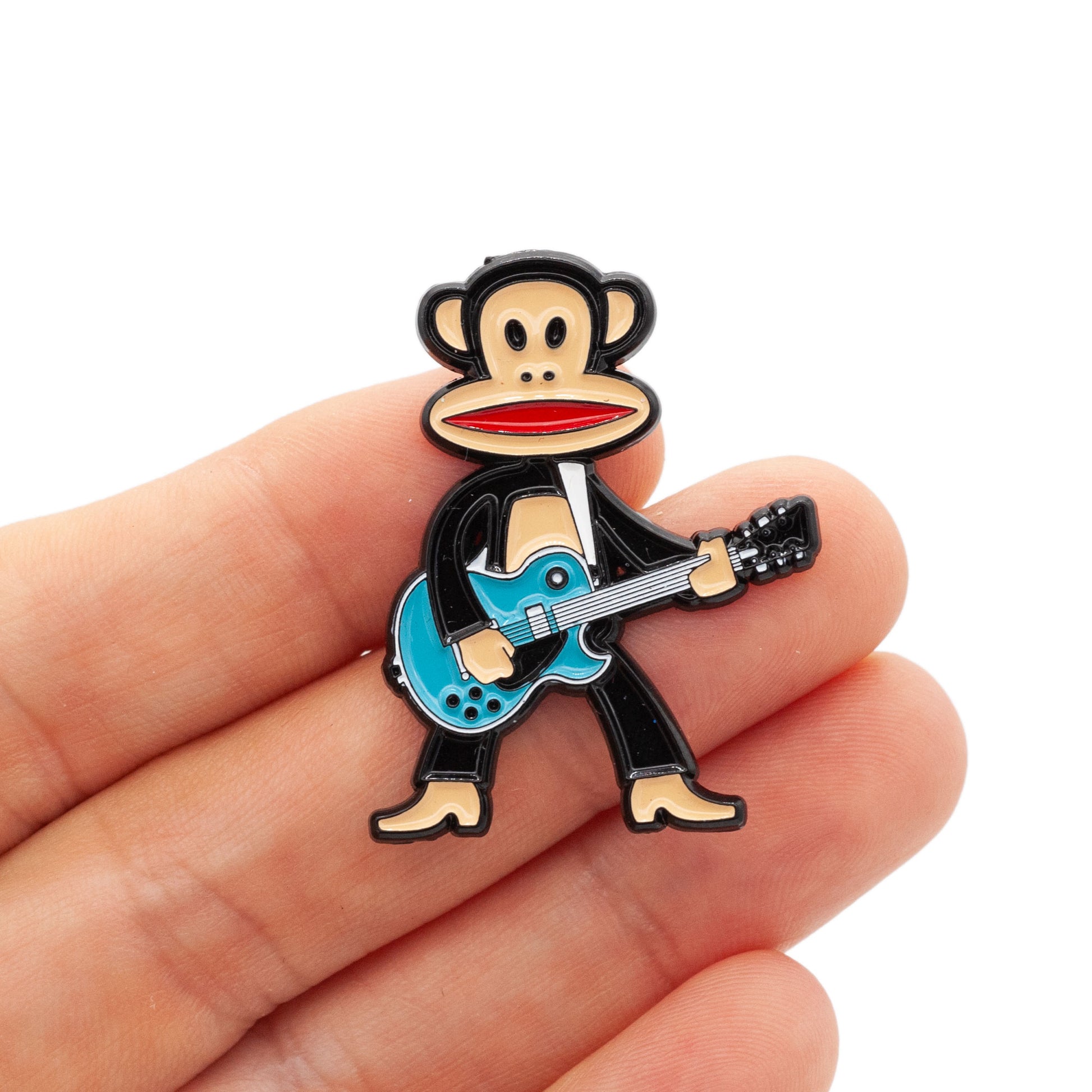 Julius the monkey is standing tall and rocking with his teal colored guitar! Julius has his mouth open, showing red, and is shot being held by a hand against a white background