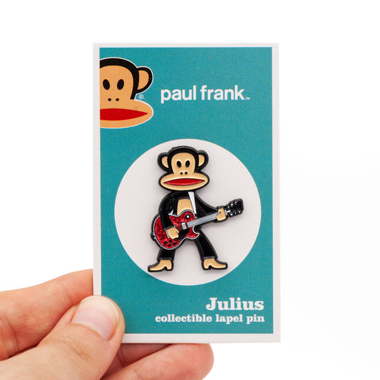Julius the monkey playing a red glitter guiter, on his backing card, shot against a white background.