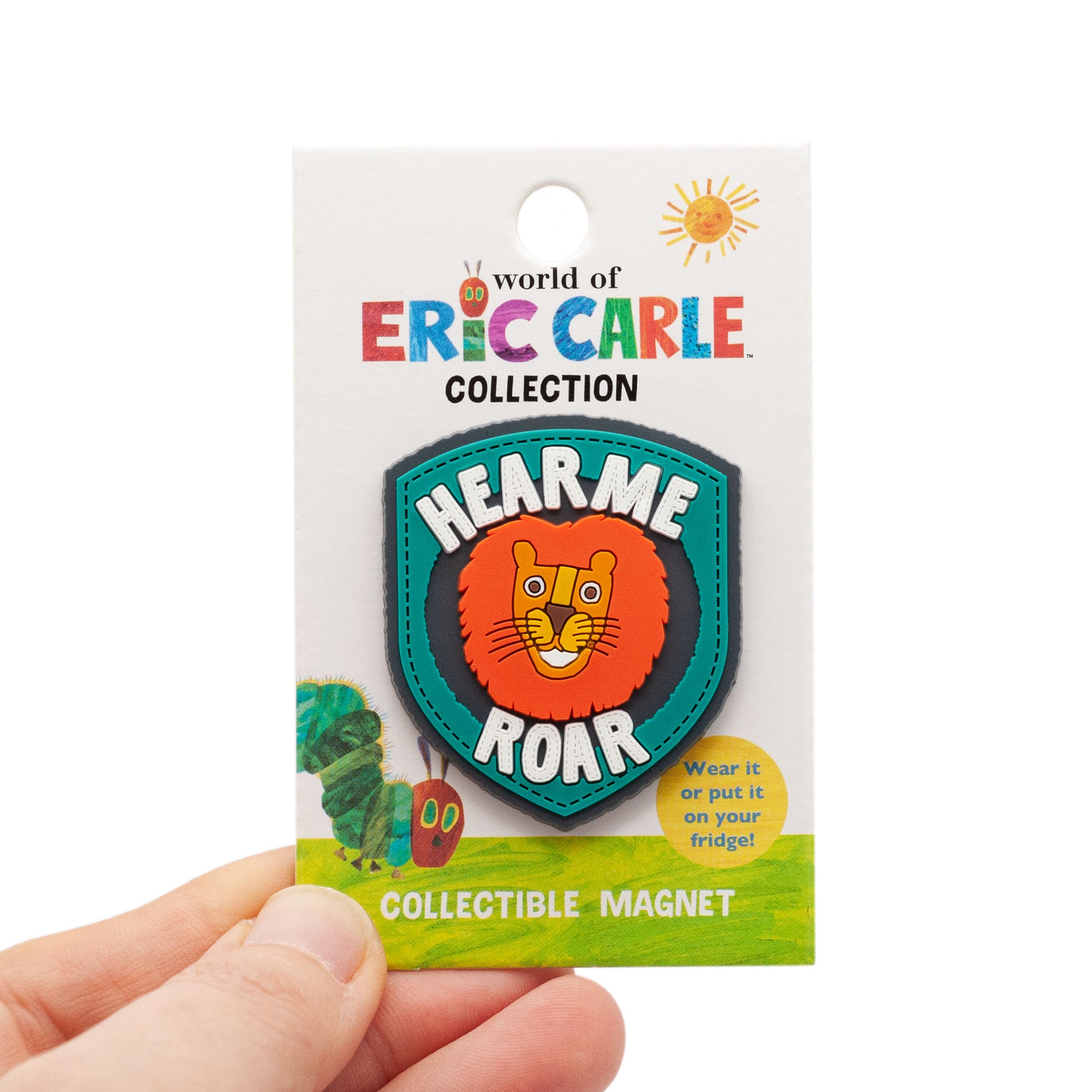 The Very Hungry Caterpillar PVC enamel pin on white background. Caterpillar has a red face with yellow and green eyes , with purple antennas, and a light green and dark green body. magnet is over top of World of Eric Carle backing card.