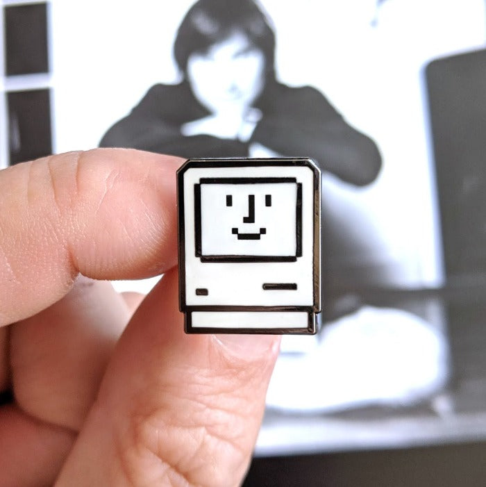 Personal computer icon with a smiling face inside.. Pin is over top of a photo of steve jobs.