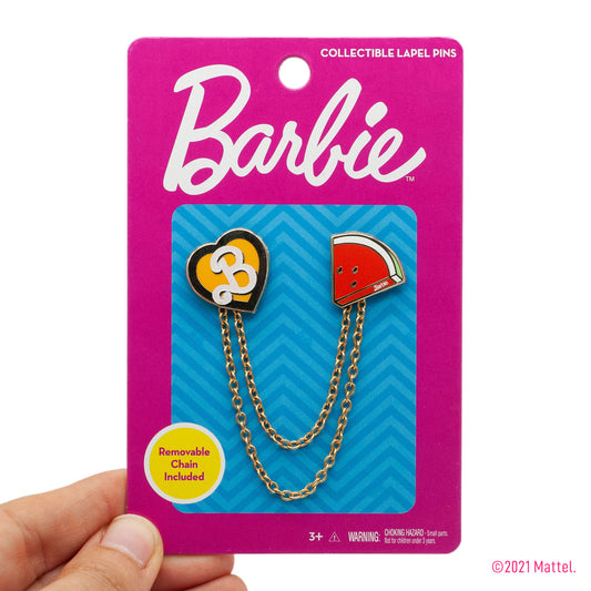 two barbie enamel pins connected by two removable chains on packaging . gold heart with white "B" on it and a pink watermelon pin. 