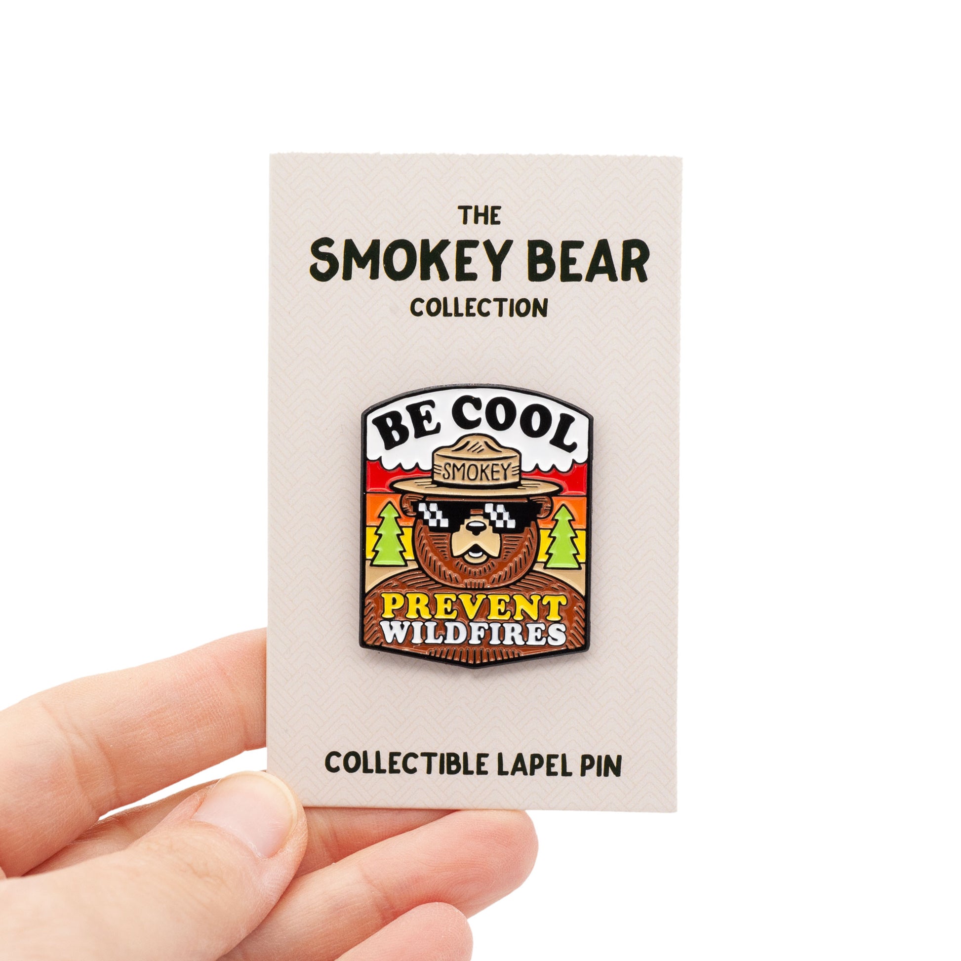 smokey bear with cool sunglasses on and a forest background. type says "be cool, prevent wildfires". On backing card, being held by hand, over white background.