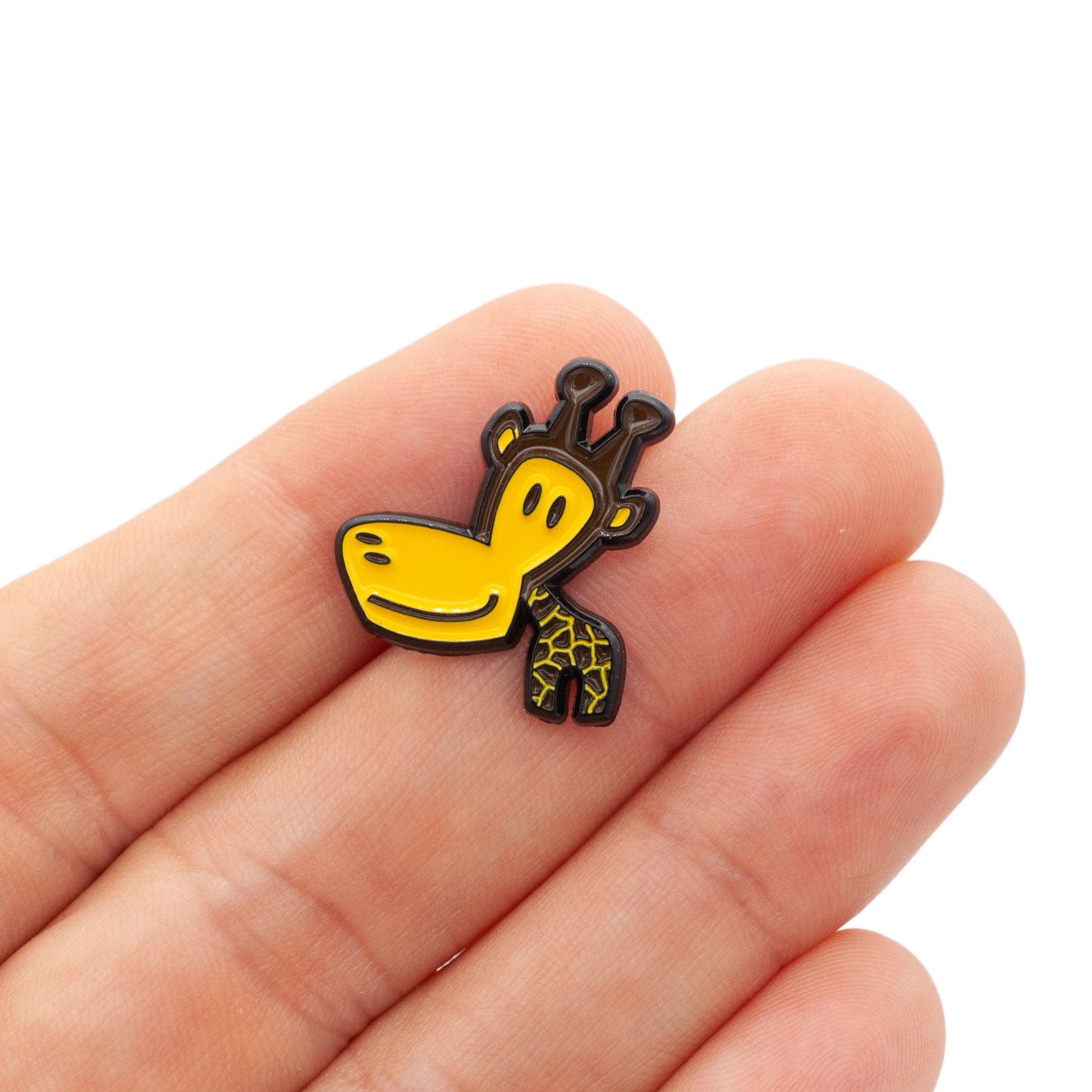 small brown and yellow giraffe pin resting on hand, over white background.
