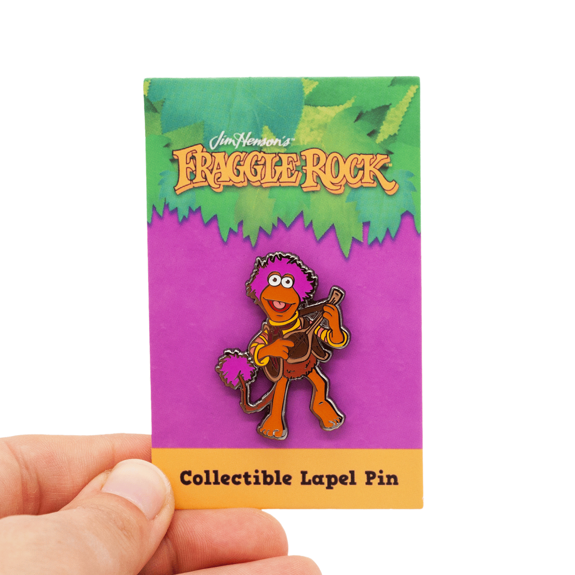 gobo lapel pin, featuring the character of gobo playing his favorite instrument! Pin is on a Fraggle Rock backing card, being held by hand, over white.