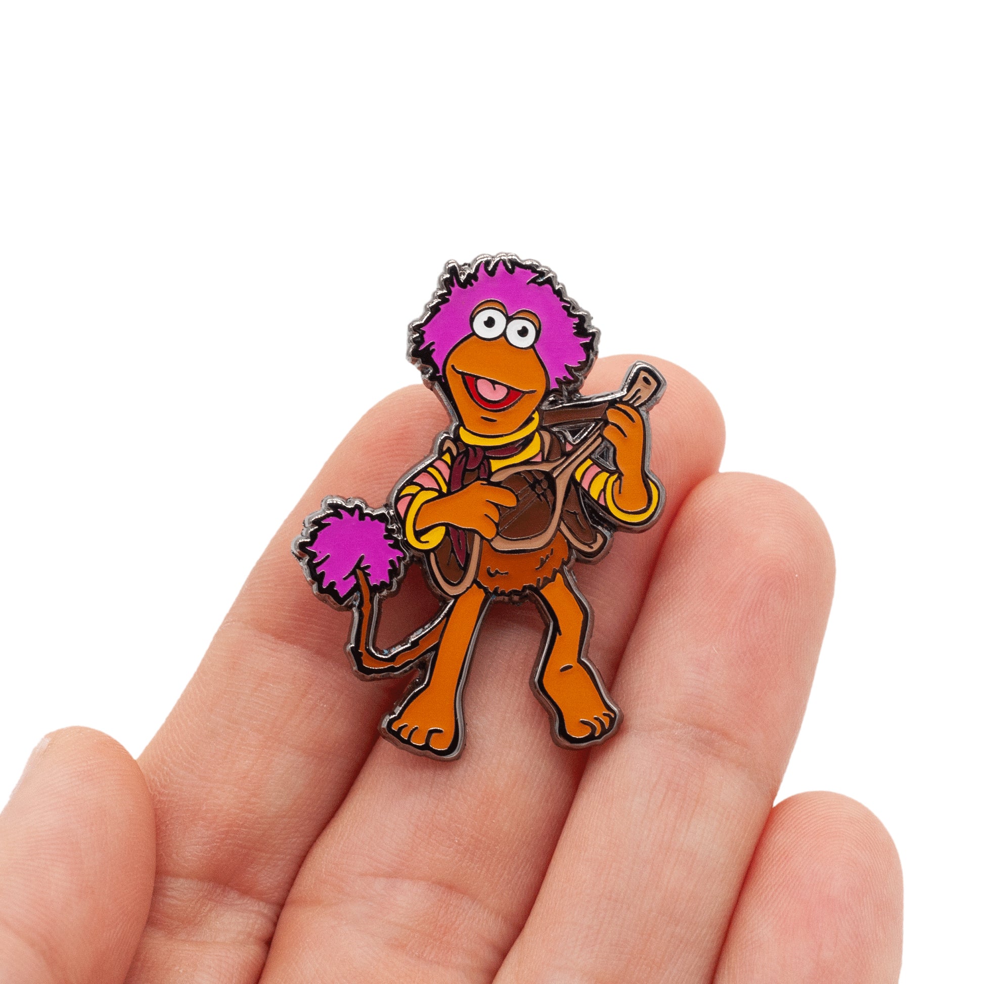 gobo lapel pin, featuring the character of gobo playing his favorite instrument! Pin is being held by a hand, over white background. 