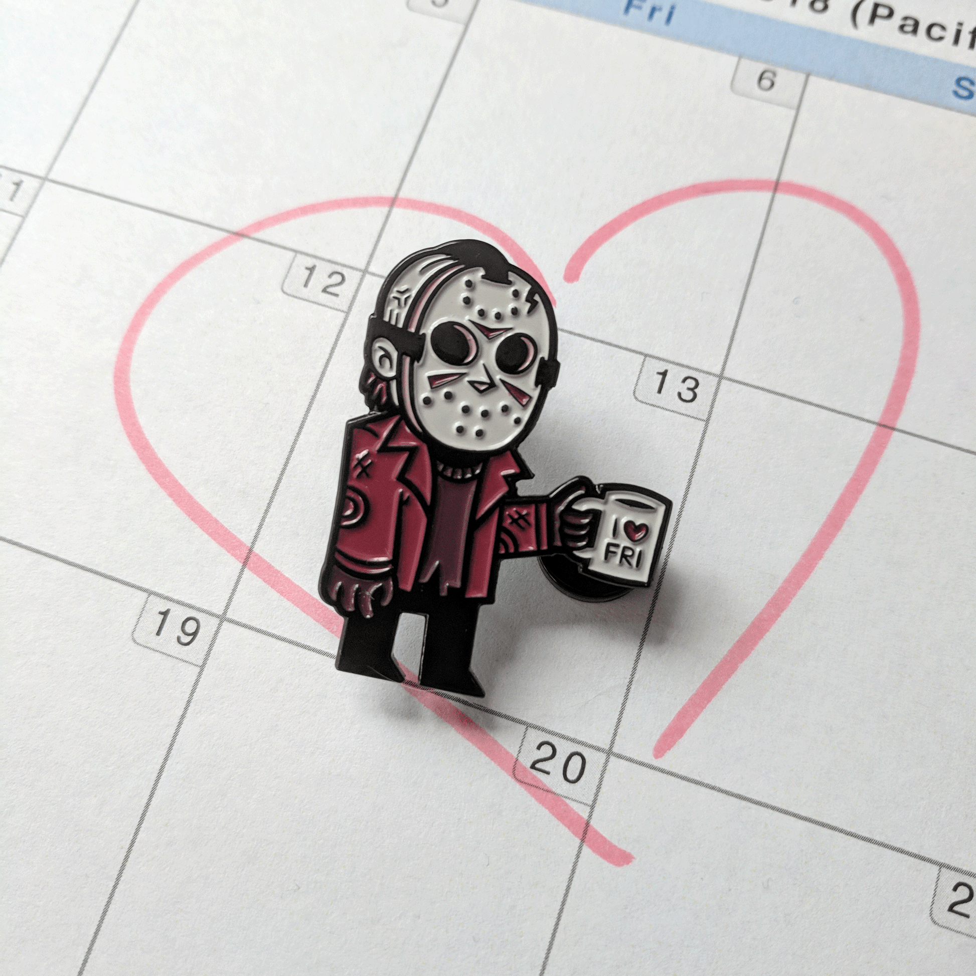 I Heart Friday Jason Voorhees Pin on top of a calendar on Friday the 13th. 