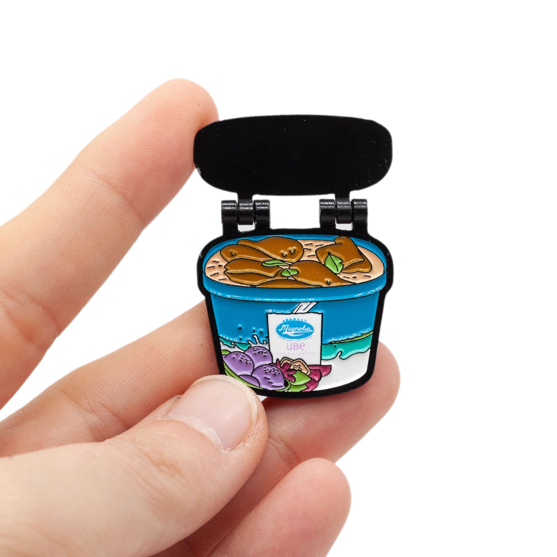 magnolia ice cream tub enamel pin that hinges open to reveal frozen chicken adobo. The ultimate Filipino Tupperware! Pin is held by a hand over a white background.